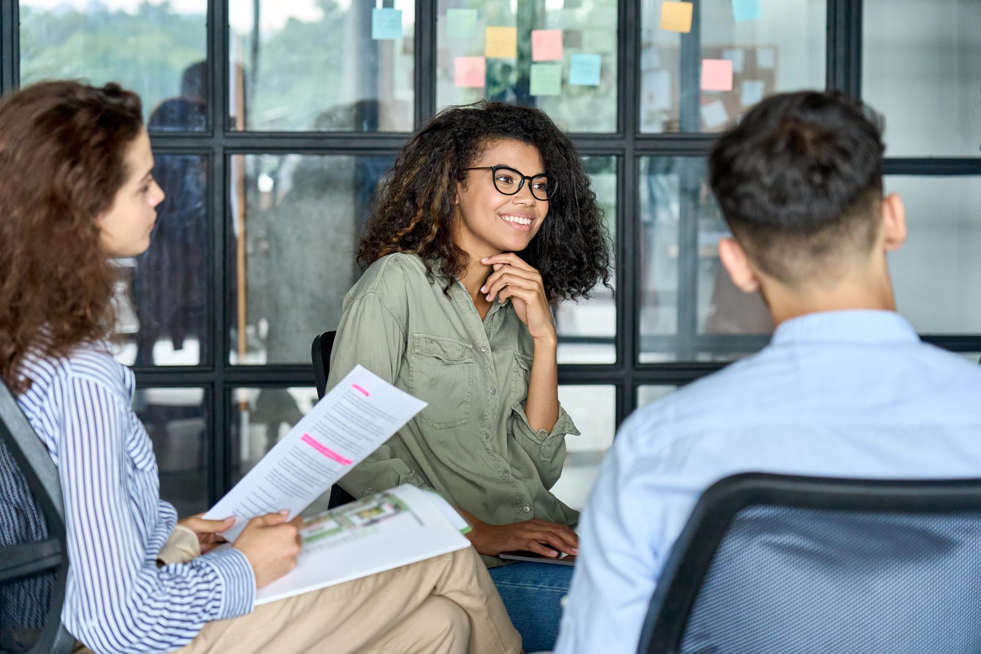Team members in a relaxed conversation reviewing documents